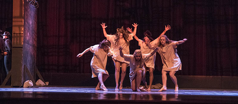  Five dancers with arms outstretched strike a pose onstage