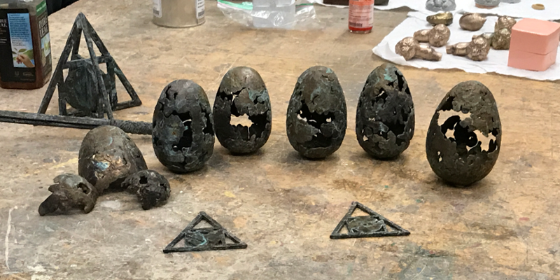 Several brass eggs arrayed on a worktable