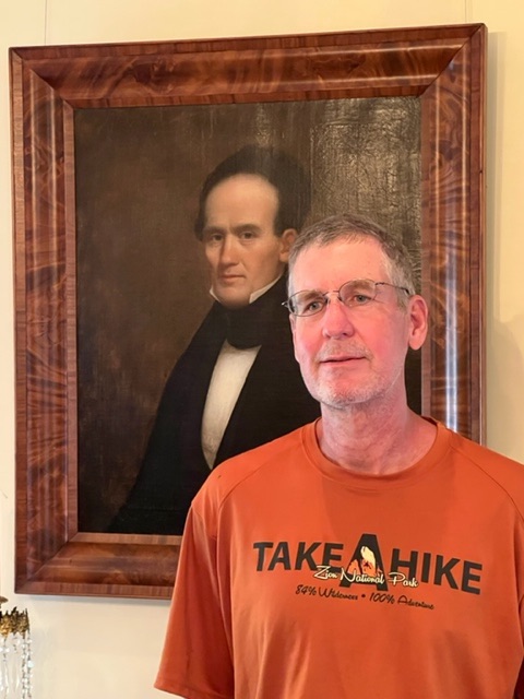Andy McGuffey poses next to portrait of WH McGuffey