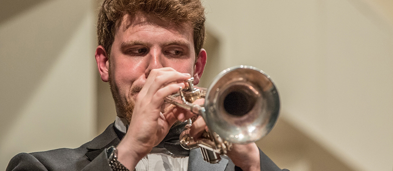 A trumpet player faces forward as he performs