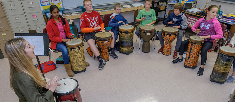 A student teacher leads her class in a percussion performance