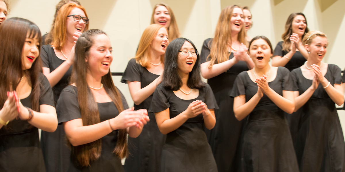  A group of smiling and clapping Choraliers in concert