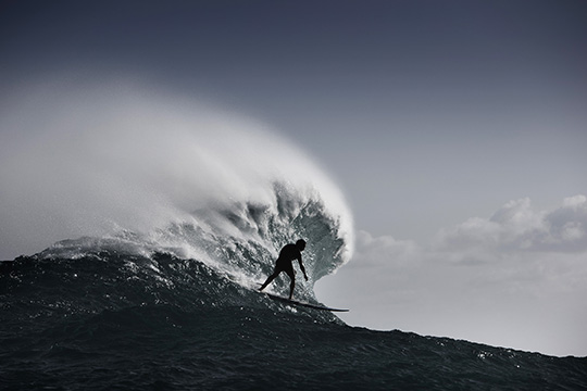 A surfer at the crest of a wave in artwork entitled Mouth of Jaws