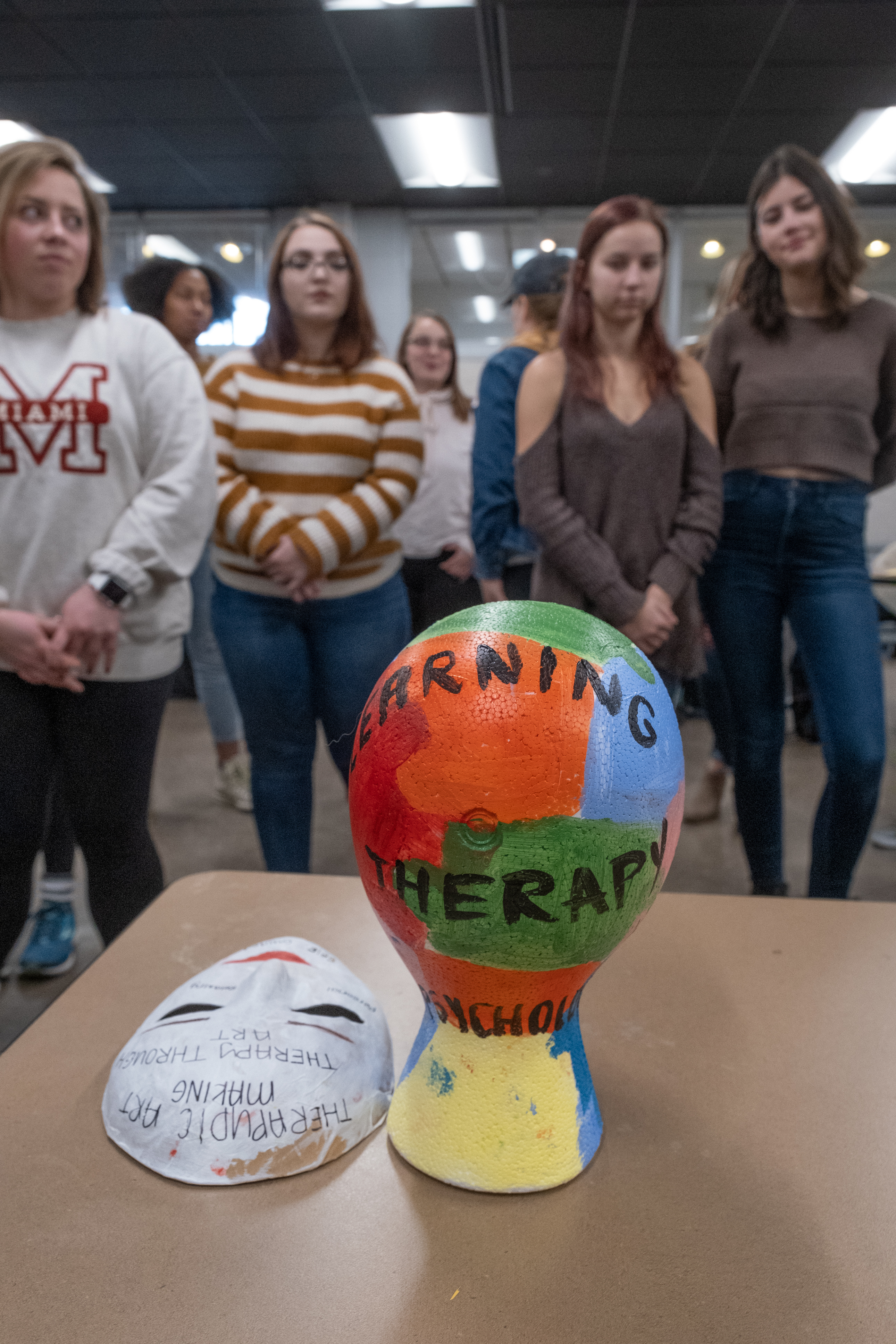 Students examine artworks displayed on a table