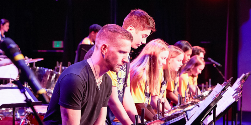 JLB is in foreground as a row of students perform on steel drums