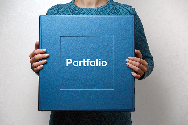 A person holds a square that reads 'portfolio'
