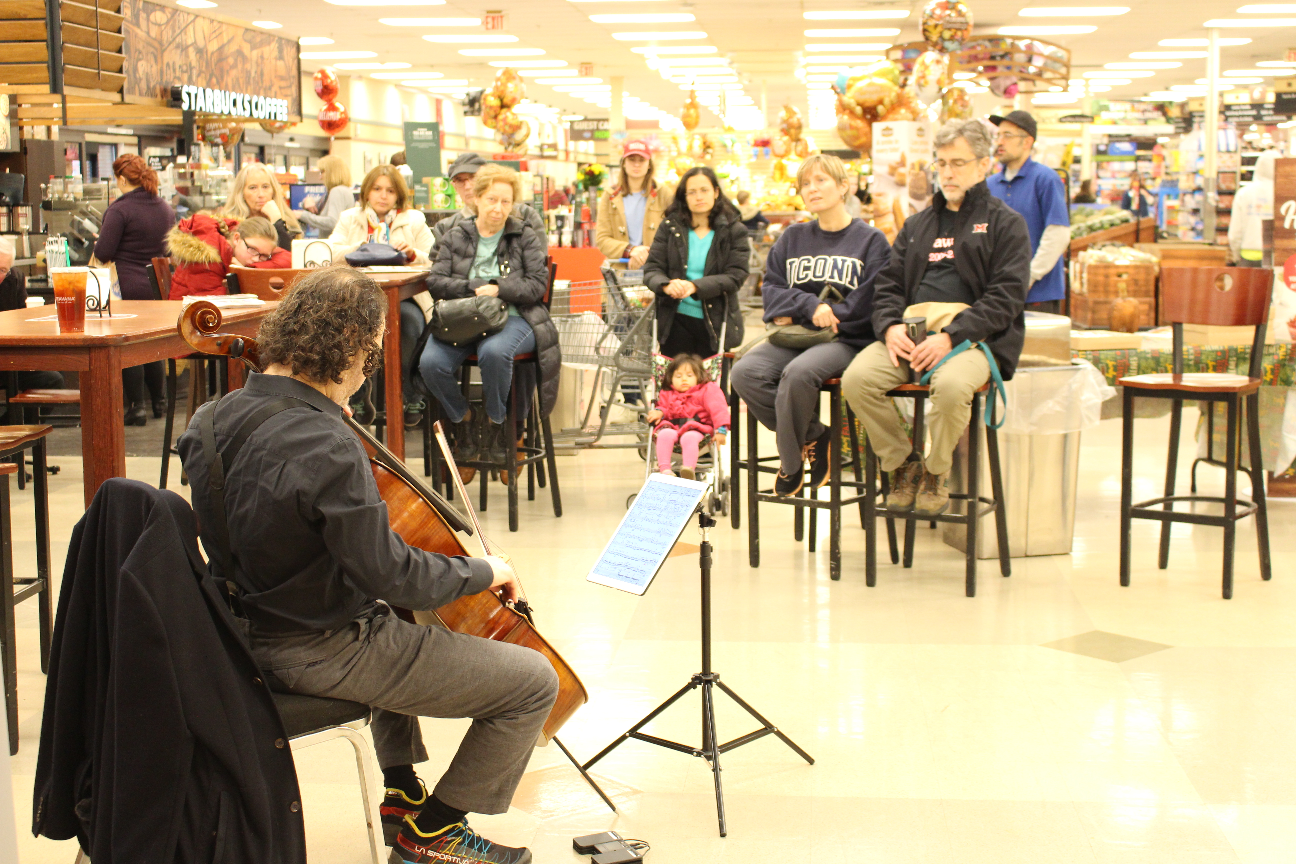 Matt Haimovitz playing cello at Kroger with people watching him perform in front of Starbucks