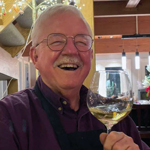 Jack Keegan smiling and holding up a glass of white wine
