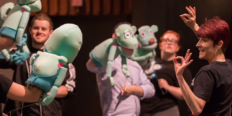 Actors and puppets receive direction during a rehearsal of Avenue Q