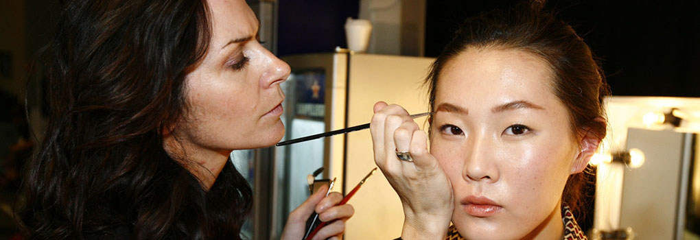 A makeup artist applies makeup to an actress's face