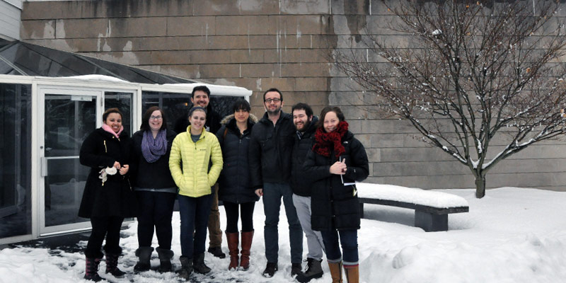 Students and visiting designer wearing winter coats standing outside a museum in the snow