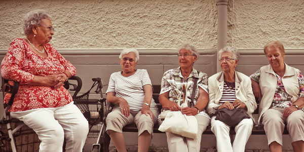elderly women sitting on a bench talking