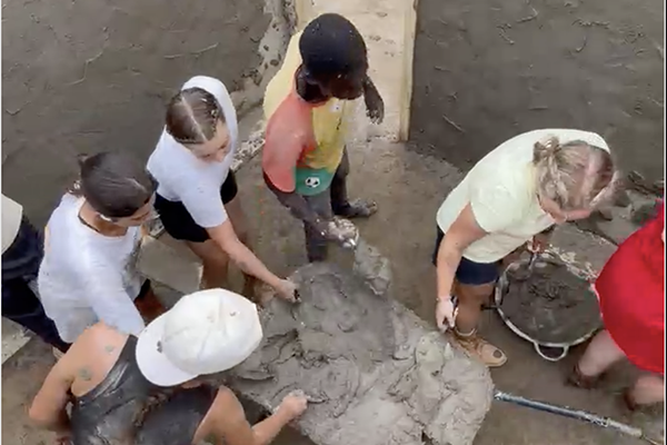 Students retrieving cement from a wheelbarrow