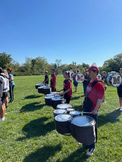 Students playing marching sextet and bass drums in a drumline