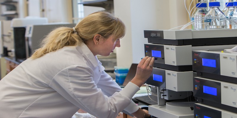 Female student wearing a lab coat conducting research in a lab
