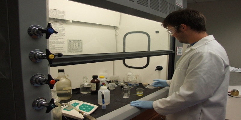 Male student working with chemicals under a fume hood