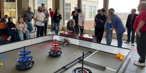 Students and faculty members watch the First Tech Challenge robots compete