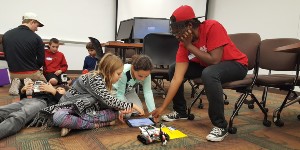 Students helping kids use a robot during kode2learn day