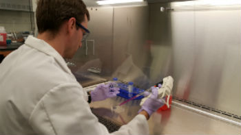 Male student in a labcoat working on a lab