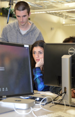 Female student works on a computer while male student looks over her shoulder