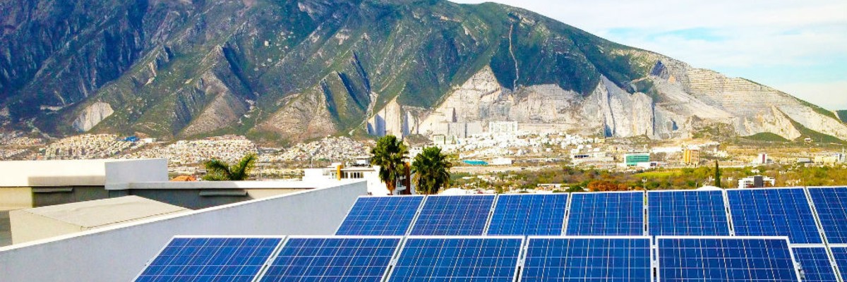  Two rows of solar panels in the foreground with a town and mountains in the background