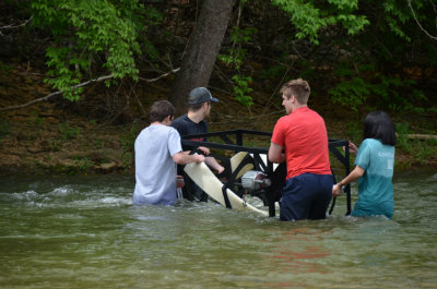 Students wading in the water of a river while holding their sustainable energy generator