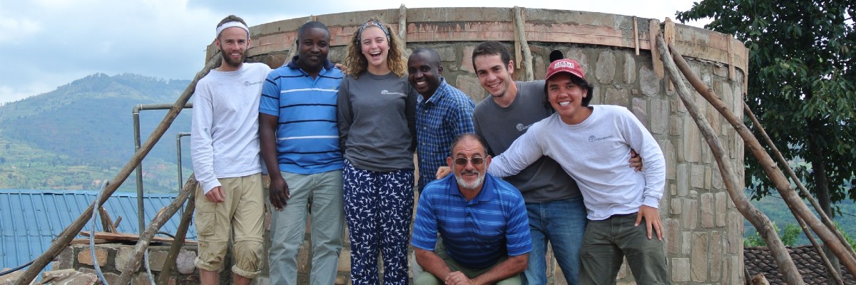 Students take a picture in front of the water tank they built in Rwanda