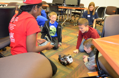 Students showing kids a robot on the floor