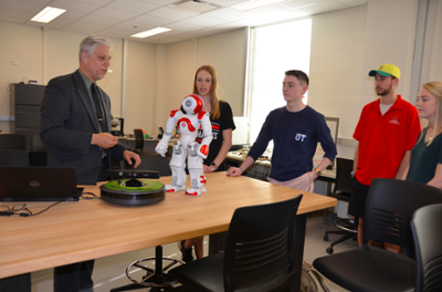 A faculty member showing students some different robots