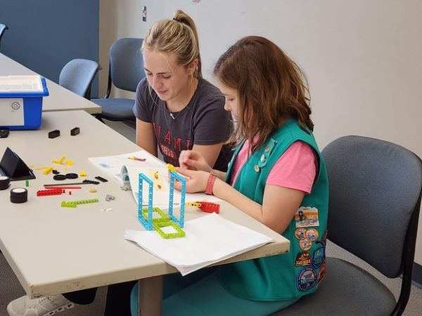 Two Girl Scouts working on a project at a table.