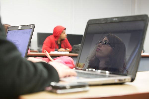 a students face reflected in their laptop