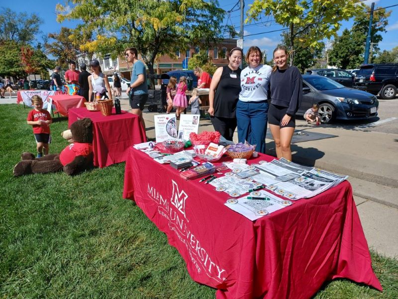 A row of tables in uptown park with red table clothes and suicide prevention related information being offered.