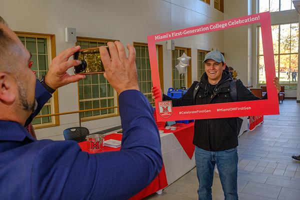 A student poses in the National First-Generation College Celebration photo frame.
