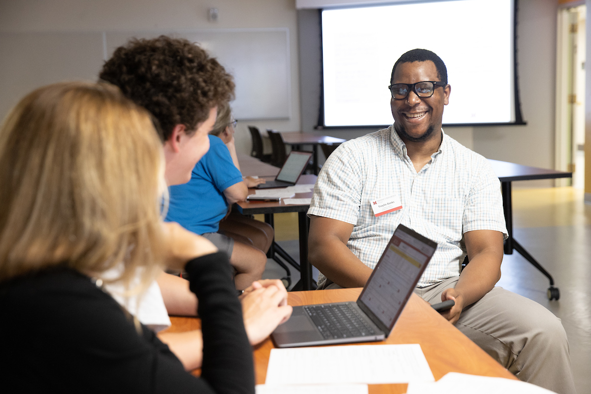 An EHS academic advisor smiles while talking to two students.