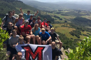 students take picture on hill with Miami flag