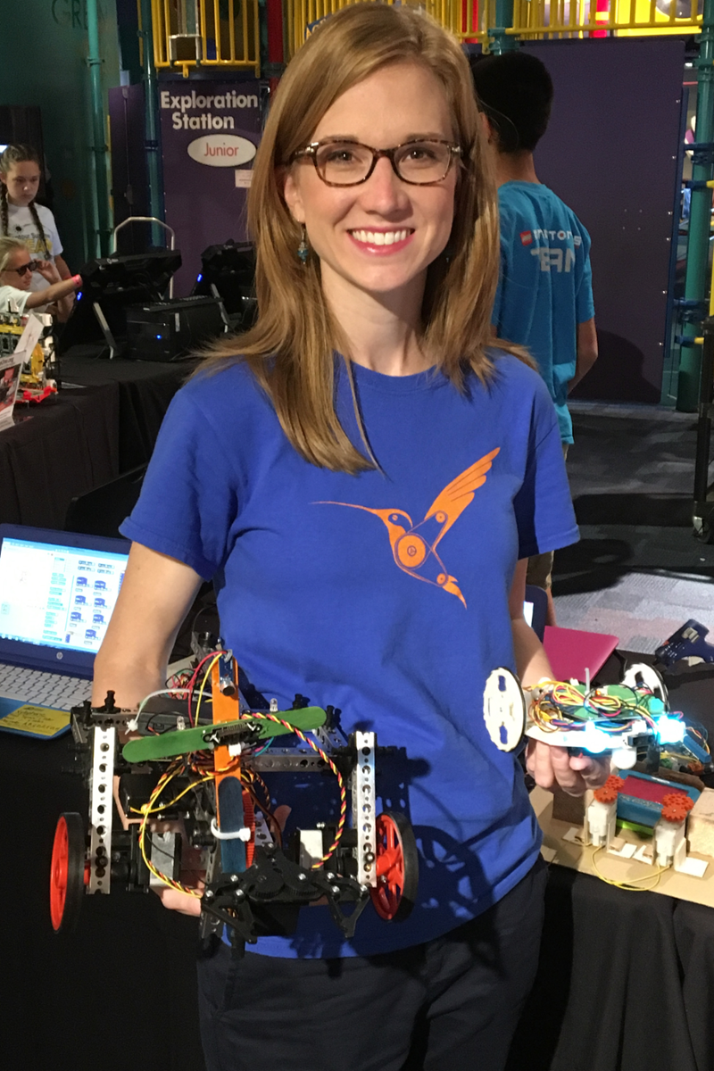 katie henry takes picture with two robots