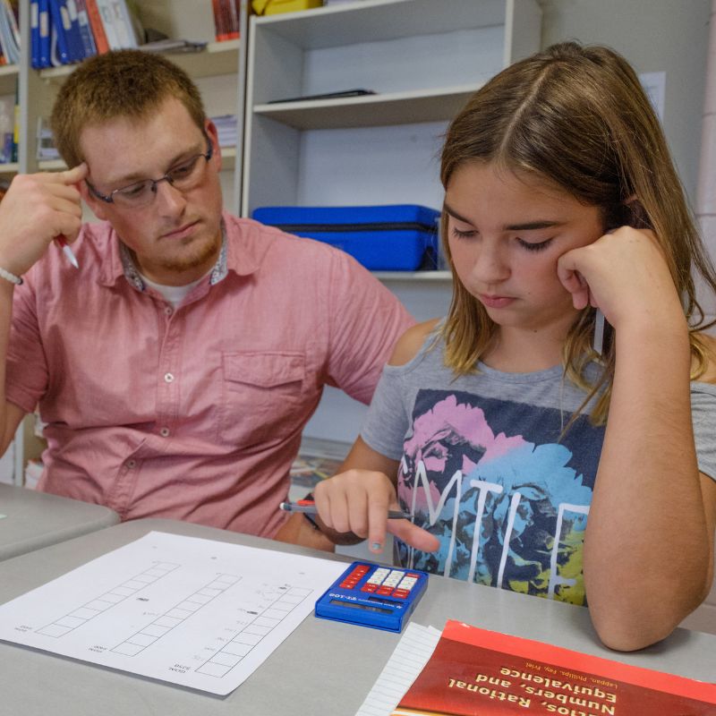 teacher working with a middle childhood student on their math