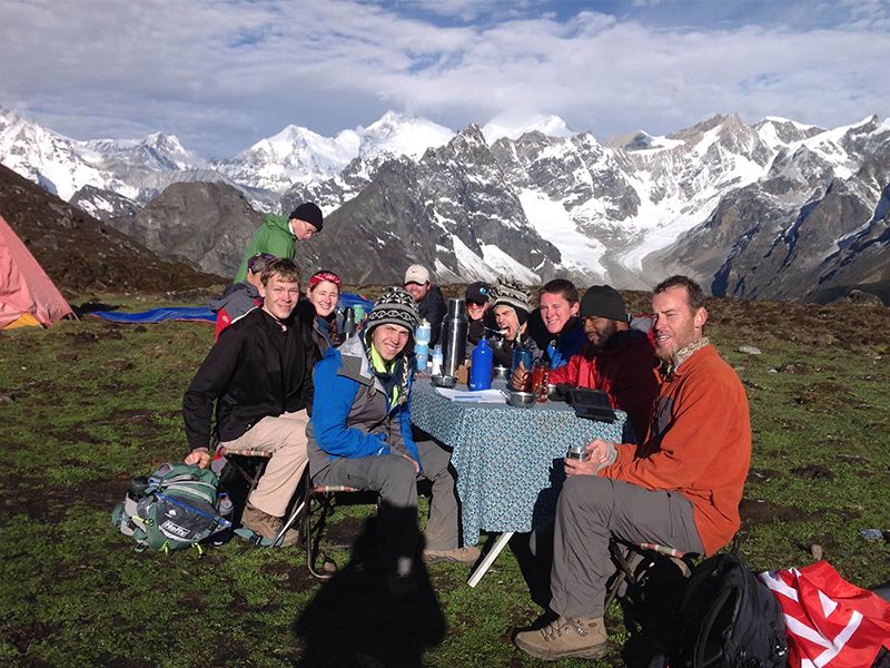 a group of students sitting together with a mountain in the background