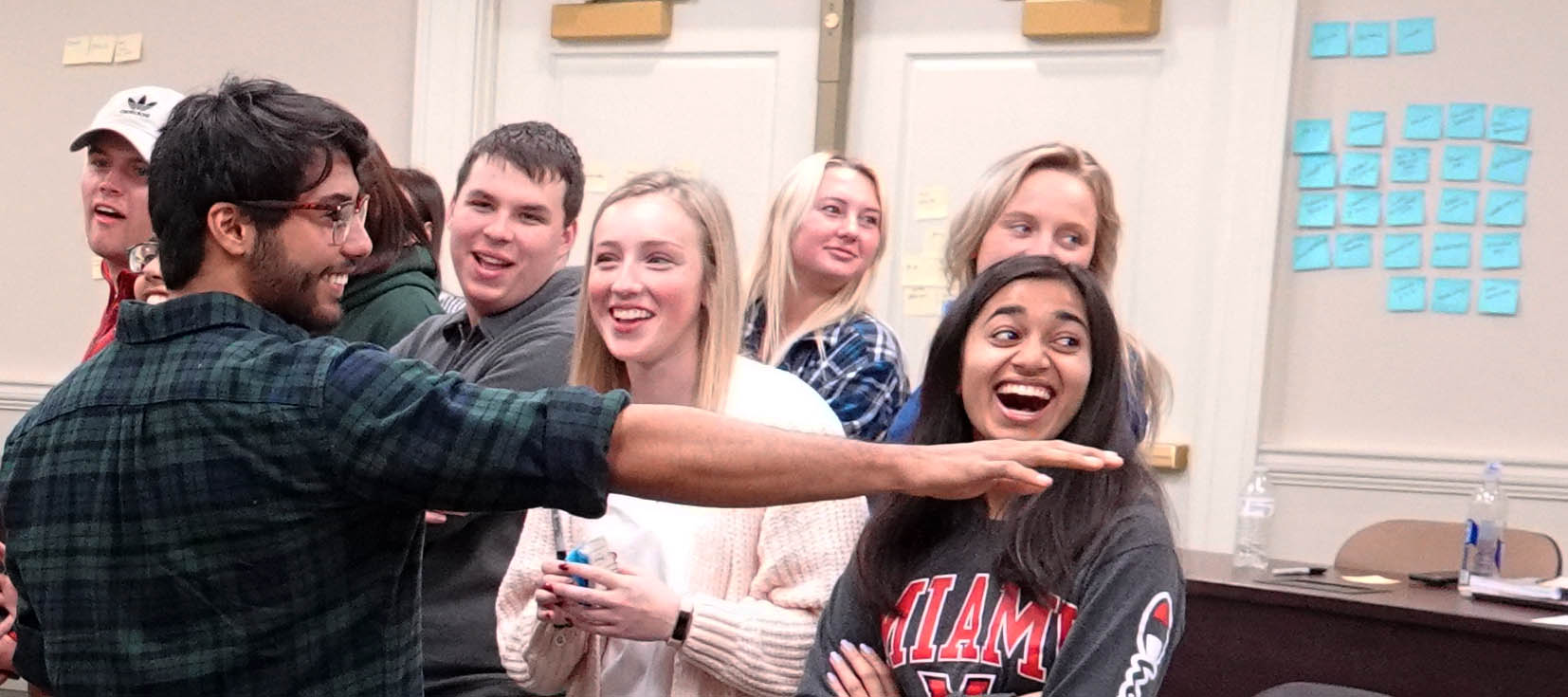  Male student pointing as female students laugh