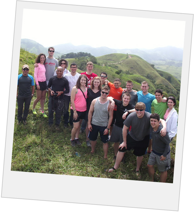 group of students posing on a large hill with hills and mountains in the background