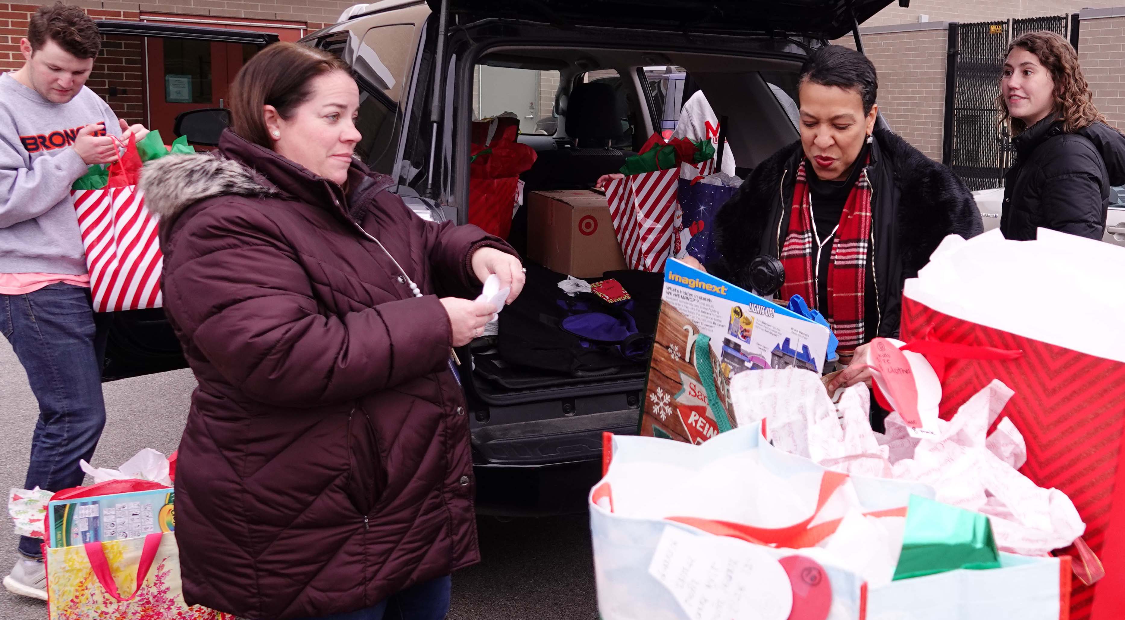 Volunteers look at collected gifts being taken from a minivan