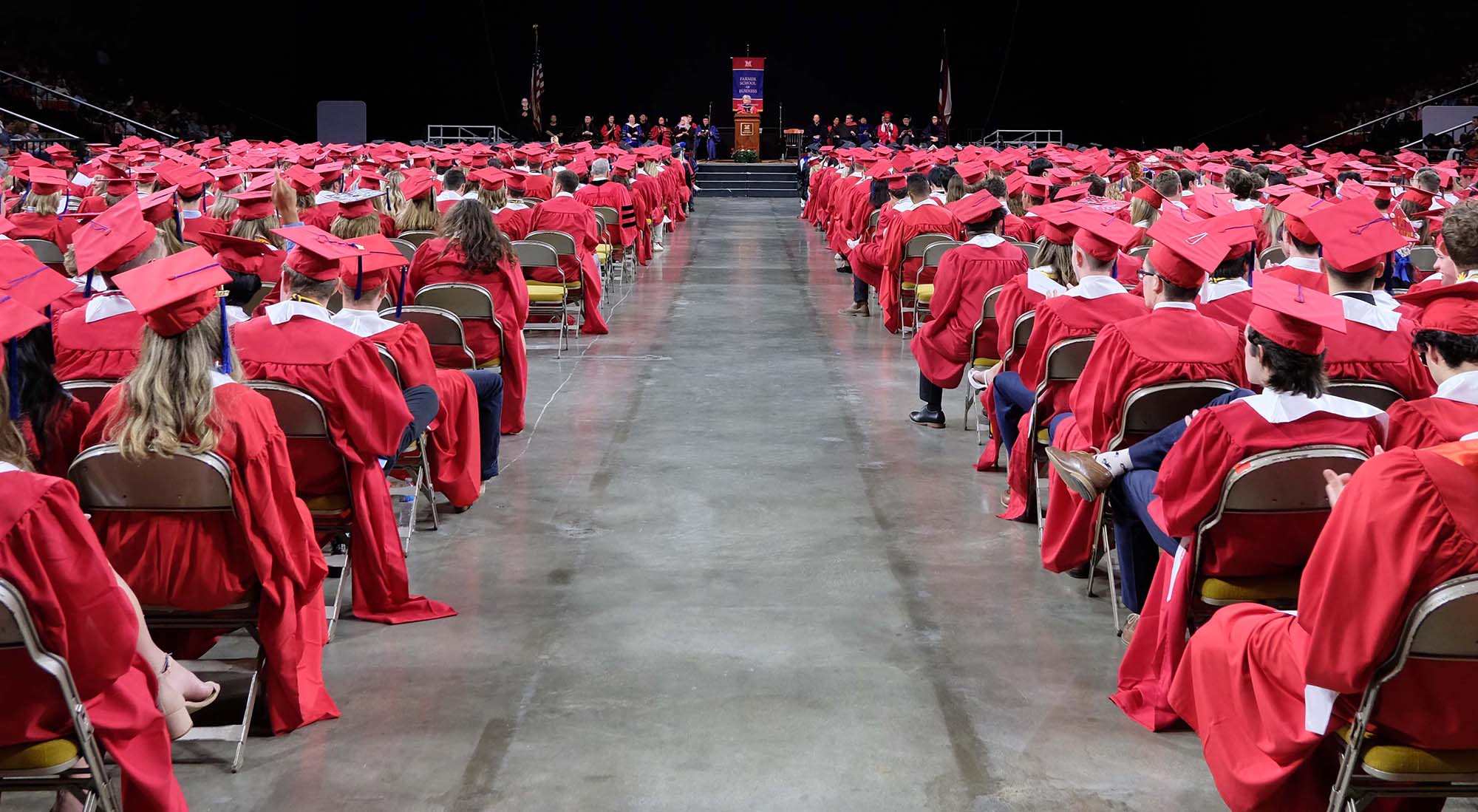 Photo of seated graduates looking toward stage from behind