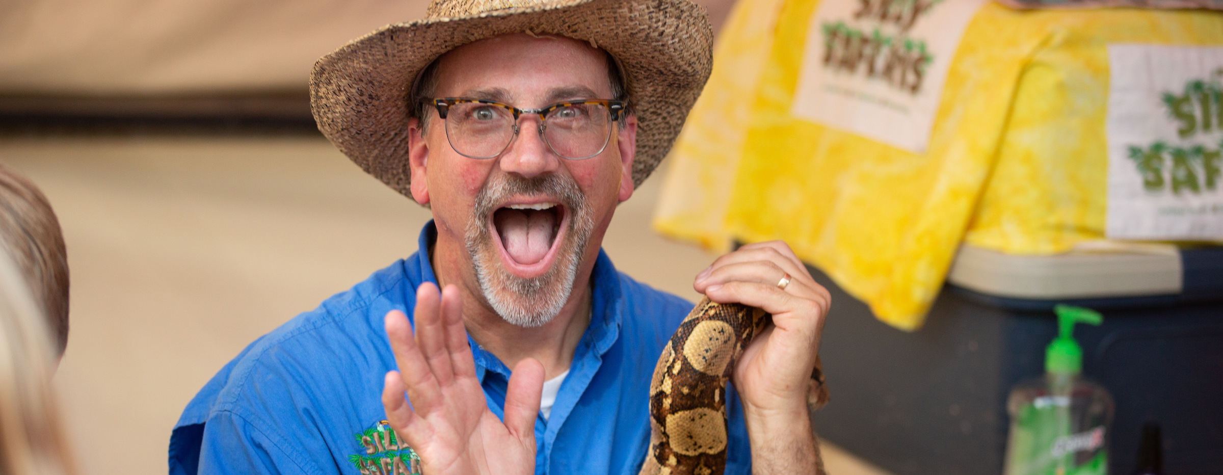 Amazon John holds a snake and makes an excited face at the camera