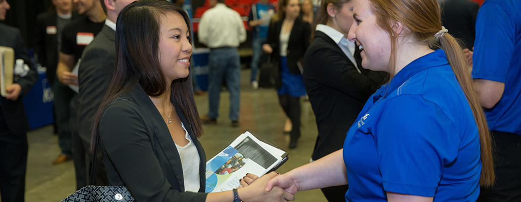 A young woman shakes hands with an employer at Career Fair