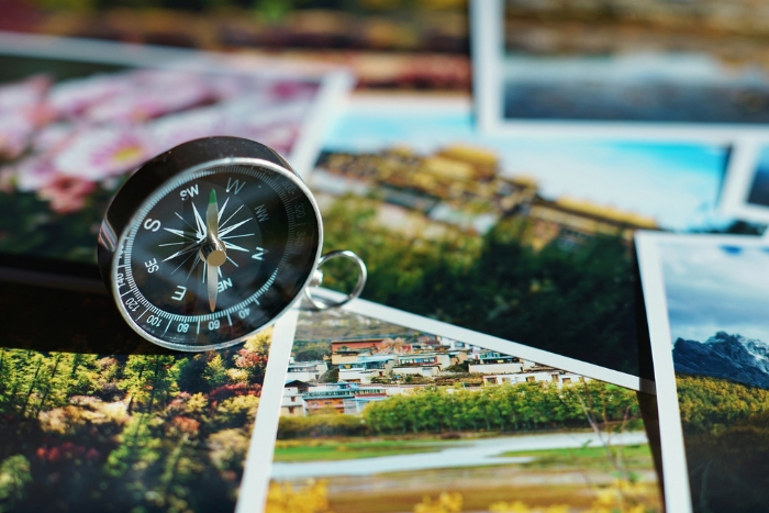 travel photos overlapping each other, compass on top that points to west
