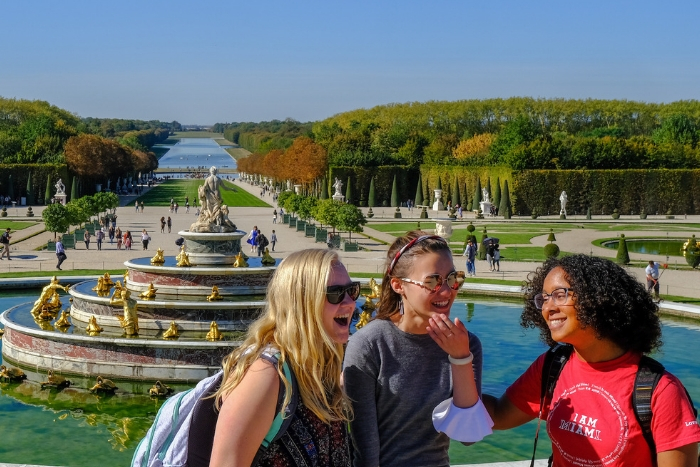 three study abroad students in Paris at Versailles gardens, smiles, laughing, wearing Miami shirt