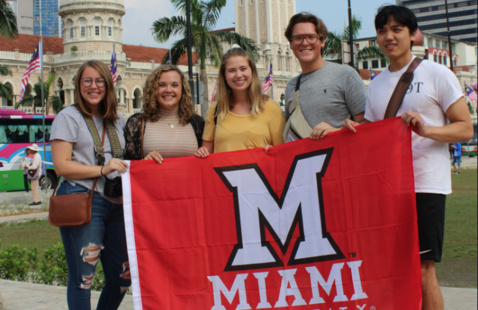 Study abroad students holding an M flag