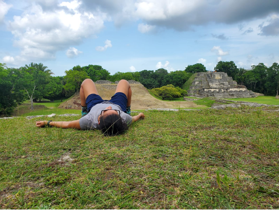 The writer lies on her back and looks up at the sky, with distant pyraminds in view