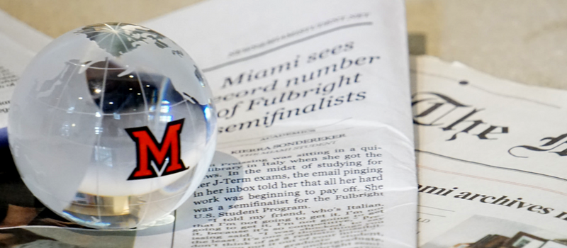 Miami student newspaper with globe paperweight on top, paperweight has Miami "M" logo on it