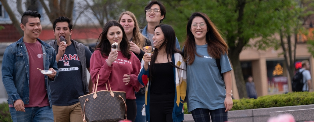 group of international and domestic students walking across the street in uptown Oxford, eating ice cream and talking with each other